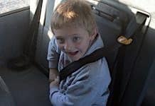File photo of a student buckling up his seatbelt in a school bus.