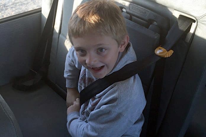 File photo of a student buckling up his seatbelt in a school bus.