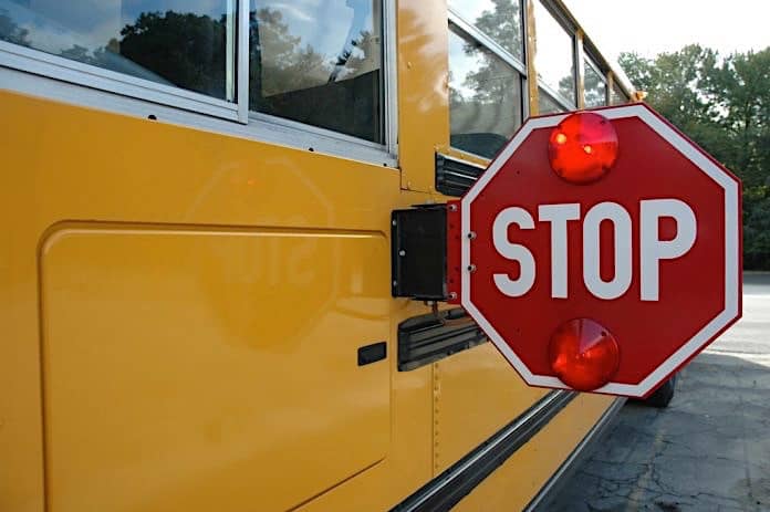School bus with stop arm deployed and LED lights flashing.