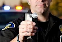 Police officer holds breathalyzer device.