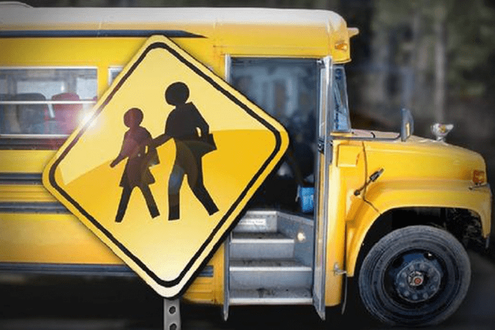 Crossing sign with school bus in background