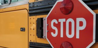 A stop arm rests flush against a school bus next to a video camera.