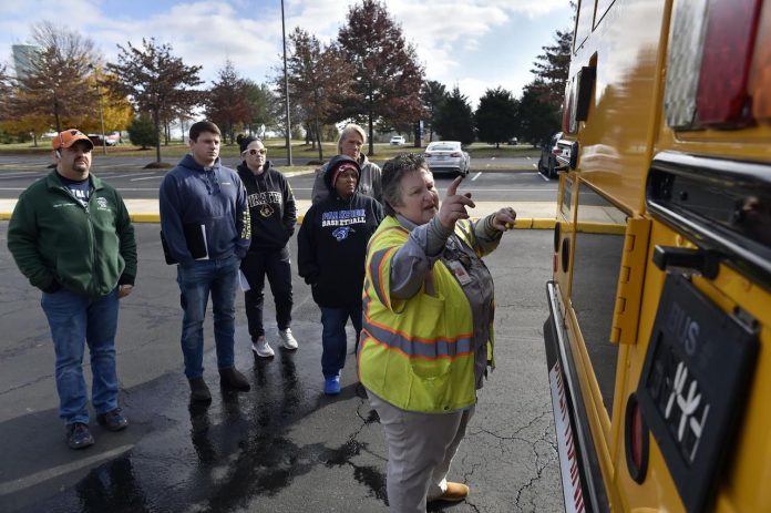 Laura Landis, a driver instructor, trainer and recruiter for Prince William County Schools in Maryland, shows teachers Kevin Loughery, Ryan Wicka, Shannon Parker, Yonika Powell, and Sharon Harrison how to perform the exterior bus inspection during a Saturday class to become bus drivers held at Parkside Middle School. (Photo courtesy of Prince William Times; photo by Randy Litzinger.)
