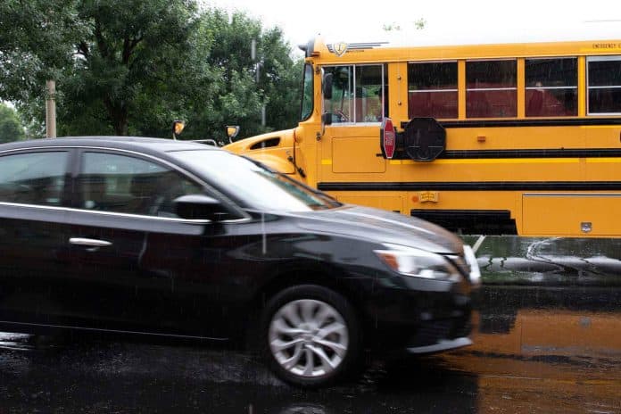 A car passes a school bus during a closed-road demonstration by Safe Fleet at the STN EXPO Indianapolis on June 9. 2019. Technology exists to both capture video of passing vehicles and alert students and bus drivers if other motorists are not stopping for the school bus. (Photo by Taylor Hannon.)