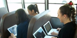 Stock photo of students using computers during the school bus ride.
