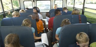Students in school bus doing homework.