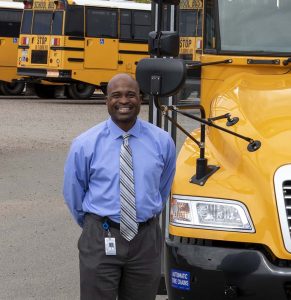 Greg Jackson, director of transportation and fleet services at Jefferson County Schools, poses with a Blue Bird school bus. (Photo by Taylor Hannon.)