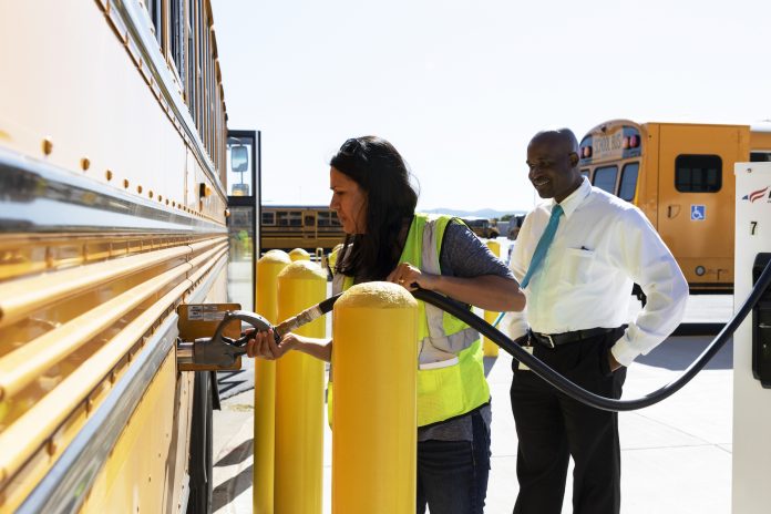 Greg Jackson, director of transportation and fleet services at Jefferson County Schools watches bus driver Maria Diaz fill up a Blue Bird propane school bus. (Photo by Taylor Hannon.)