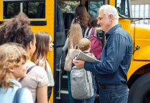 An older driver greets students as they board the school bus.
