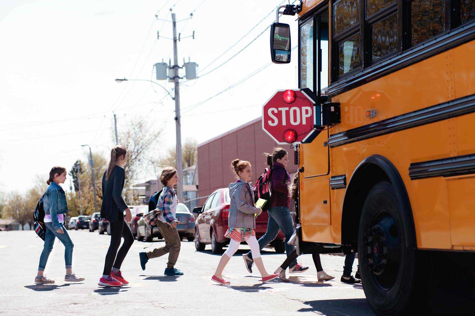 Group of elementary school kids getting in a yellow school bus.