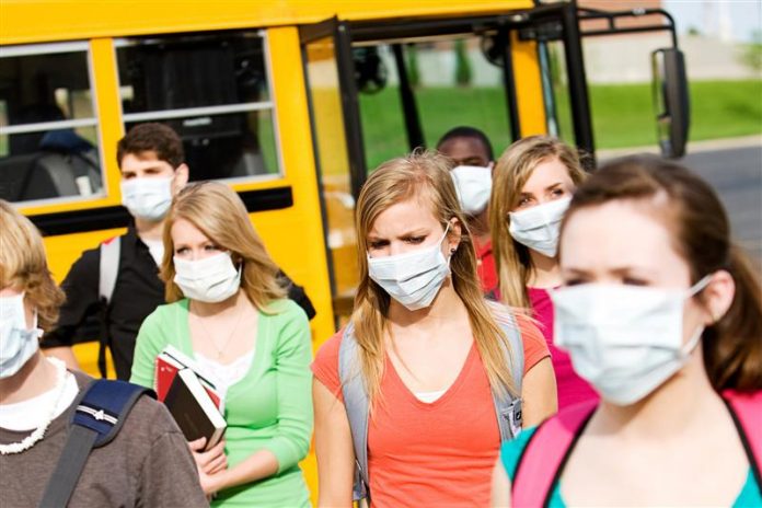 Students leaving a school bus in masks