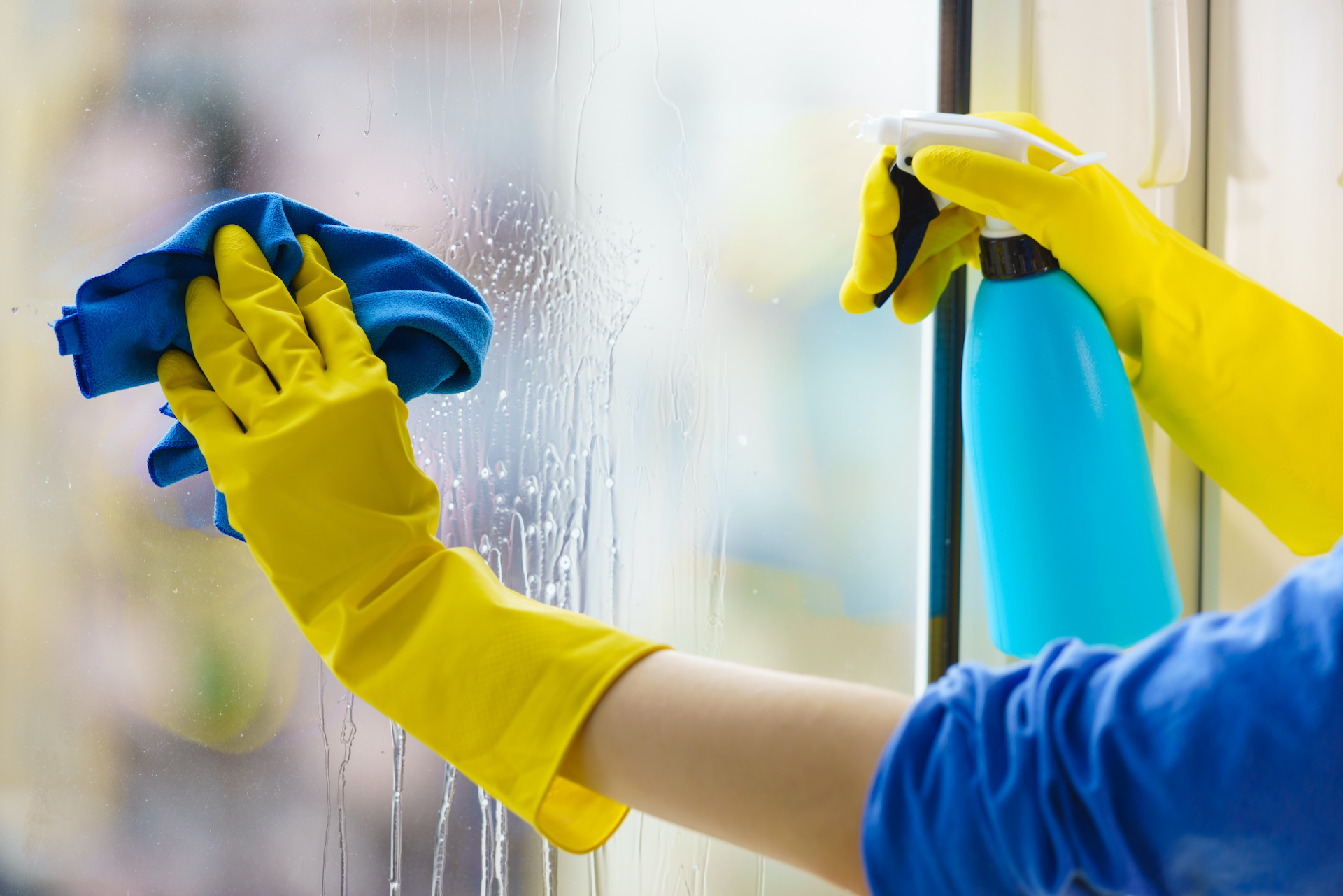 Gloved hand cleaning window rag and spray