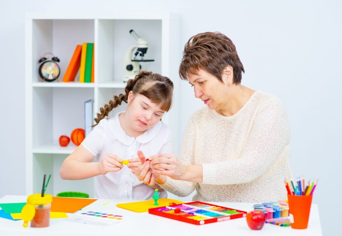 Girl with Down Syndrome works with her teacher at home