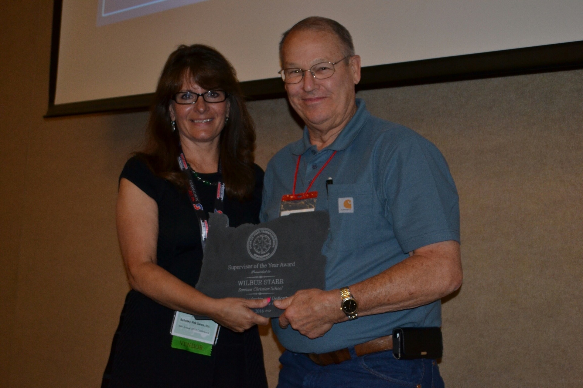 Kim Hevia presenting the Supervisor of the Year Award, on behalf of Schetky NW Bus and Van Sales, to Wilbur Starr at Santiam Christian School in Oregon.