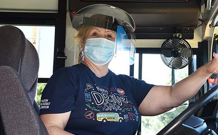 A Fullerton Unified School District bus driver in California, poses with with a face mask and shield.