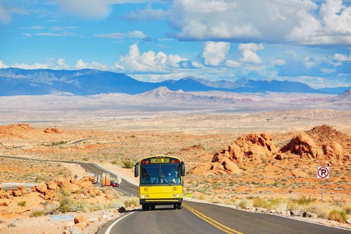 School bus driving on winding road in Valley of the Fire national park in Nevada, USA