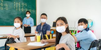 Group of Asian elementary school students and teacher wearing hygienic mask to prevent the outbreak of Covid 19 in classroom while back to school reopen their school, New normal for education concept.