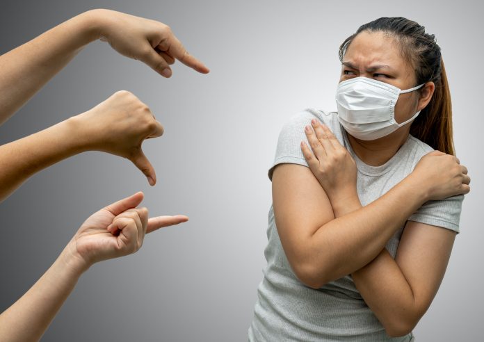 Asian woman wearing hygienic mask are bullied and hate surrounded by hands mocking her,