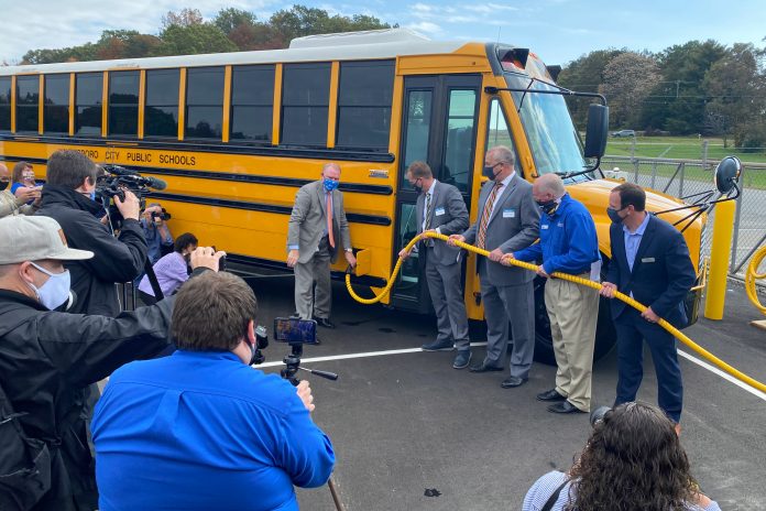 Local media photograph the cutting of a ribbon by officials of Thomas Built Buses, Dominion Energy and dealer Sonny Merryman, as they welcome the first electric school buses to Virginia during an event on Tuesday, Oct. 27, 2020.