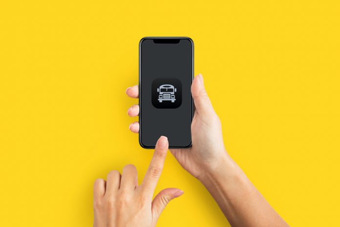 Mockup of female hands touching cell phone with blank screen on yellow background.