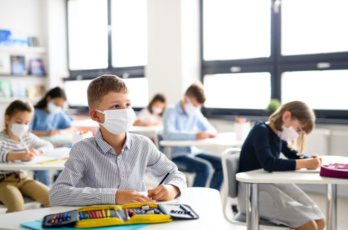Small children with face mask back at school after covid-19 quarantine and lockdown.