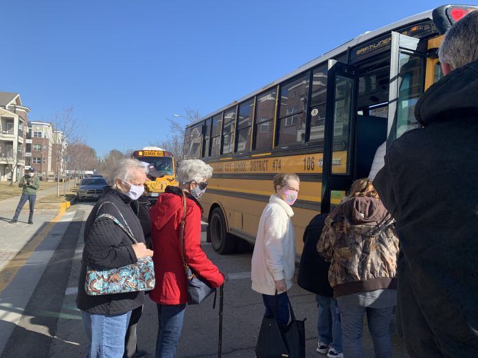 Resident of a long-term care facility board North Kansas City school buses to be transported to a COVID-19 vaccination site.