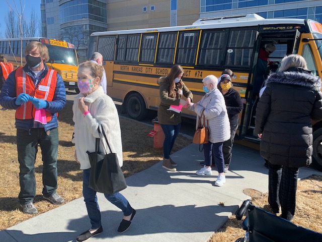 Residents exit a school bus on their way to get vaccinated.