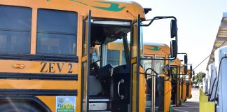 A row of electric school buses charge at Stockton Unified School District in California.