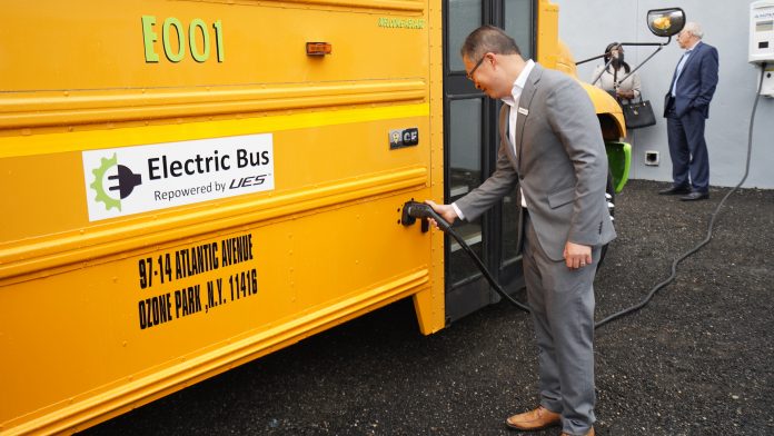 Vic Shao, CEO of AMPLY Power, plugging in the new electric school bus at New York City's ribbon cutting ceremony on June. 3, 2021.
