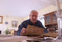 Anthony Miller reads a newspaper from his time as director of transportation for Prince George’s County Public Schools in Maryland, where he ended a long-held practice of all-black school bus routes to ensure schools remain segregated. The entire district segregated years before a U.S. Supreme Court ruling since vacated that required school districts to use school buses to integrate black and white students. Photo by Taylor Hannon.
