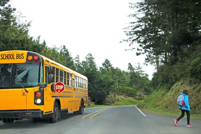 Student crosses the street away from school bus stop.