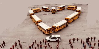 School buses form a heart and employees lock hands.