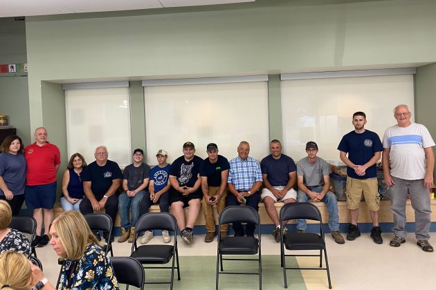 Zuk, seated wearing blue plaid shirt, sits with local firefighters during his retirement party. Zuk is a former fire chief and president of Westerlo Fire Department.