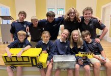 Members of the St. Bridget Catholic School robotics team poses with their national championship winning model of a school bus that could be used for last-mile delivery of goods when not transporting students.
