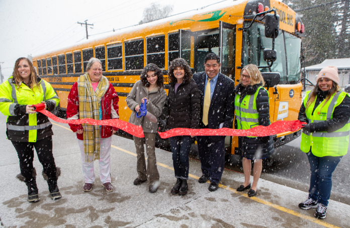 First Student and Gresham-Barlow School District officials near Portland, Oregon, cut the ceremonial ribbon on Feb. 23, 2023, to officially welcome the school bus contractor's first electric buses in the state.
