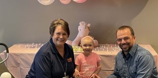 Olivia, a 3-year-old cancer survivor, poses with Cheryll Hill, assistant director of transportation, and Kayne Smith, director of transportation, during her visit to the Westgreen Transportation Center on Jan. 2, 2023.