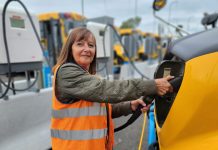 Woman charges a First Student electric school bus.