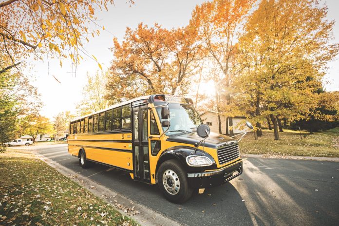 Propane autogas bus driving a school route in the fall.
