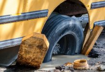 Stock image of a school bus stuck in a pothole.
