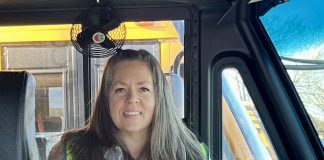School bus driver Valerie Higley poses with her published book “Shaman Rides the School Bus,” to teach safety to children and their parents. Shaman the Goat plushie is also available for pre-order.